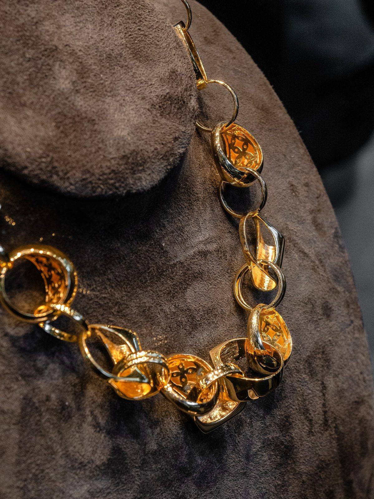A gold and silver chain of oval links on brown suede